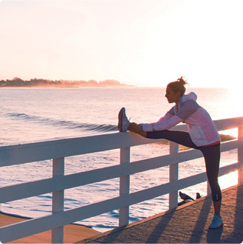 Jogger stretching on a fence overlooking the ocean